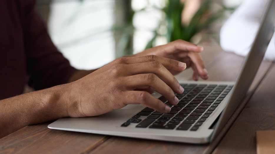 Fingers typing on a laptop