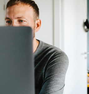 A man watching a computer screen. A children's room is seen in the background. 