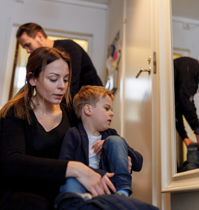 Family of four getting dressed in hallway.
