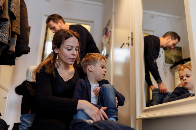 Family of four getting dressed in hallway.